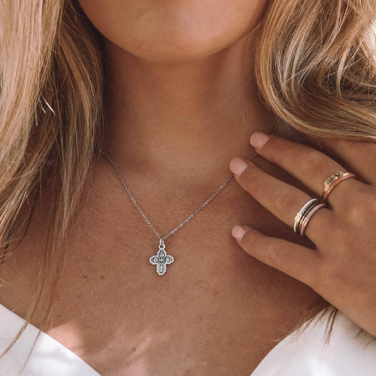 A close up of a woman wearing a silver 4-way cross chain necklace