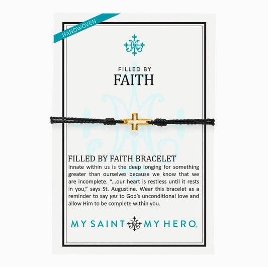 The display card for a pull bracelet featuring a gold cross outline.  Display card reads "Handwoven", "Filled by Faith", talks about the bracelet, and has the My Saint My Hero logo at the bottom of the display card. 