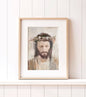 Framed artwork featuring a Crowned Jesus sitting on a white ledge against a white wood wall.