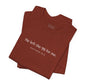 A folded rust-colored shirt that reads "He left the 99 for me. Matthew18:12"