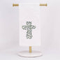 A hand towel featuring a cross out of greenery, displayed on a towel stand.