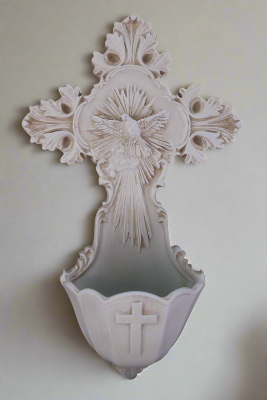 An ornate Holy Water cross font featuring a dove as the depiction of the Holy Spirit with rays around the dove.  At the bowl of the font, there is a plain embossed cross.